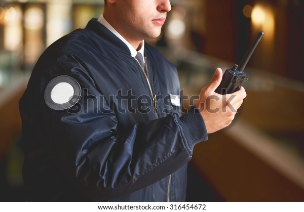  a cut face close up\
in a security guard with a portable wireless transceiver on a\
blurry background