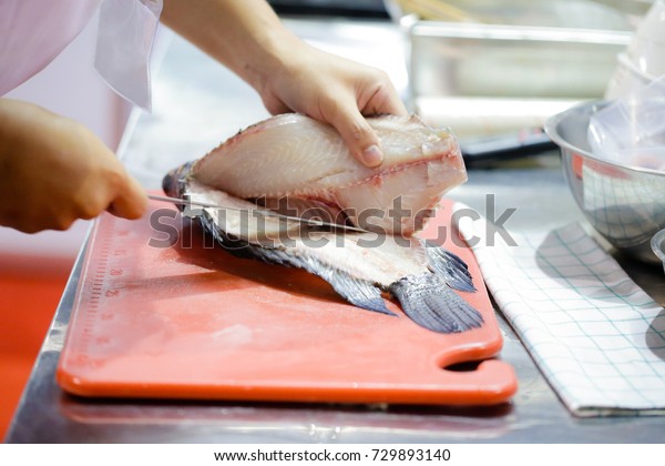 cut fish fillet in a fish shop, chef cutting red\
fish in the kitchen