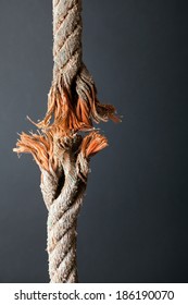Cut And Frayed Rope Hanging By A Thread And Ready To Break On Dark Background