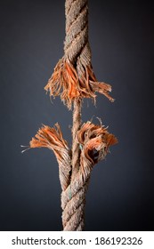 Cut And Frayed Rope Hanging By A Thread And Ready To Break On Dark Background