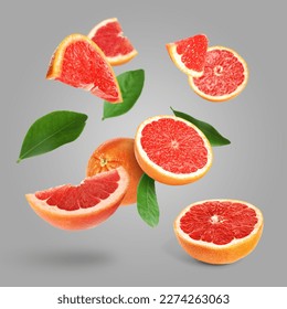 Cut fresh grapefruits and green leaves flying on grey background - Shutterstock ID 2274263063