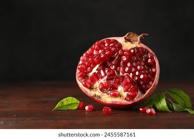 Cut fresh pomegranate and green leaves on wooden table, space for text - Powered by Shutterstock