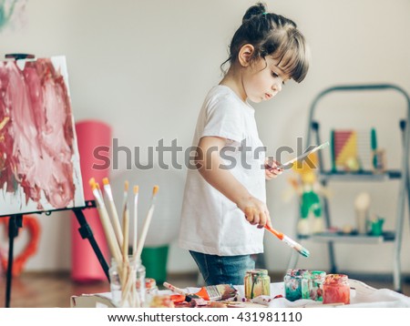 Cut girl painting in at her  home. Selective focus and small depth of field.