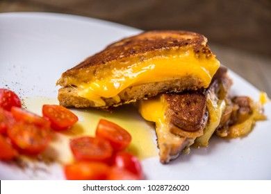 Cut Up Grilled Cheese Sandwich On A White Plate With Tomatoes 
