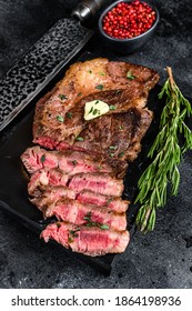 Cut Grilled Chuck eye roll beef meat steak on a marble board. Black background. Top view. - Shutterstock ID 1864198936