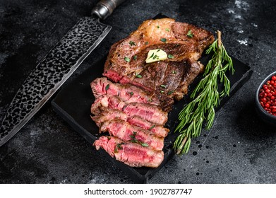 Cut Grilled Chuck Eye Roll Beef Meat Steak On A Marble Board. Black Background. Top View.