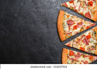 Cut into slices delicious fresh pizza with mushrooms and ham on a dark background. Top view . Pizza on the black table. - Shutterstock ID 514537924