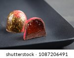 Cut luxury handmade candy with chocolate ganache and red confiture filling on black background. Exclusive handcrafted bonbon 