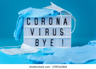 Cut medical mask and crumpled medical gloves on a blue background, light box with text corona virus bye