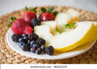 Cut Melon And Berries. Fruit Salad Of Strawberries, Blueberries, Melon, Mint And Blackberries. Diet Salad On The White Plate - Breakfast, Weight Loss Concept. Closeup. Healthy Snack.