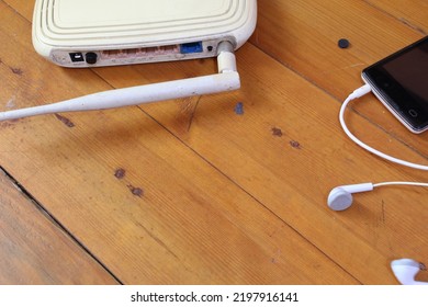 Cut Out Wifi Router, Smart Phone And Earphones On Wooden Table.  Technology Concept