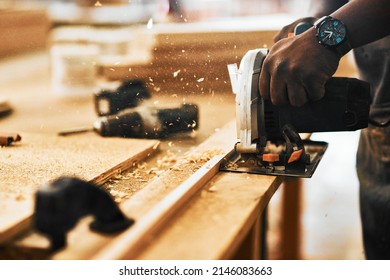 Cut to perfection. Cropped shot of an unrecognizable carpenter using a circular saw to cut wood inside a workshop. - Powered by Shutterstock