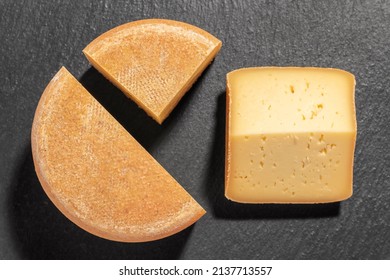 Cut piece of farmhouse aged cheese. On black slate plate. - Powered by Shutterstock