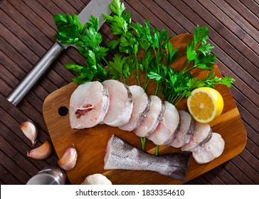 Cut Pieces Of Fresh Hake On Wooden Surface With Seasonings Prepared For Cooking