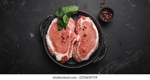 Cut raw meat pork steaks with seasonings in black cast iron pan on dark rustic stone background top view, ready for roasting. Pork loin chops cooking - Powered by Shutterstock