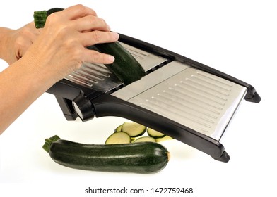 Cut Raw Zucchini With A Kitchen Mandolin In Closeup On White Background