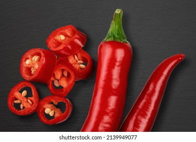 cut red hot chili peppers, Capsicum isolated on black stone background. sliced red hot chili peppers. high-quality studio shot of red long capsicum. top view