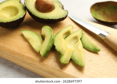 Cortar aguacates verdes maduros y cuchillo en la mesa gris claro, en primer plano