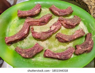 Cut And Separated Baby Back Ribs In Their Raw State, Seasoned And Placed On A Green Serving Platter.