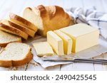 Cut slice wheat bread with butter on a light kitchen table. Tasty cut wheat bread  with fresh butter on a white wooden table.