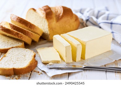 Cut slice wheat bread with butter on a light kitchen table. Tasty cut wheat bread  with fresh butter on a white wooden table.