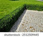 cut squares of flowerbed edging in a historic garden made of boxwood hedges. courtyard of castle along cobblestone path row of squares frozen ice, snowing  evergreen topiary, ivy, creeper, above, top