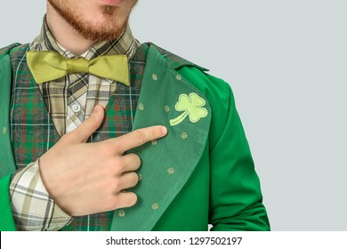Cut view of young bearded man point on clover on suit. He wear saint Patrick's costume. Isolated on grey background.
