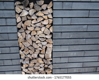 Cut wood logs ready for heating in winter stacked in storage place in a modern brick wall