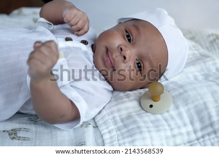 Cute 2 months old Muslim baby boy wearing white hat and Muslim Men's robe costume lying on bed 