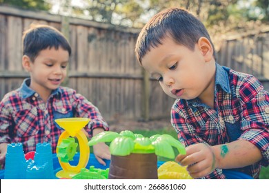 Cute 2 Year Old Mixed Race Asian Caucasian Brothers Play Happily With A Water Toy In Their Suburban House Backyard. Filtered Effects