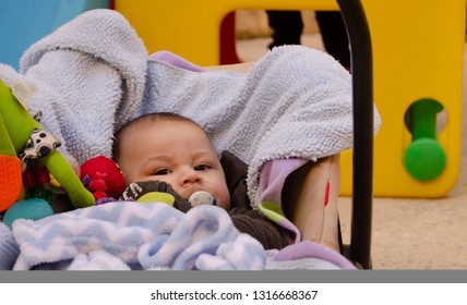 Cute 3 Months Old Baby Boy Making Funny Faces In Baby Carry Cot Outdoors