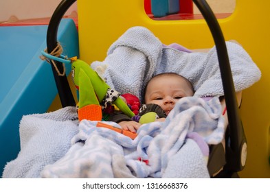 Cute 3 Months Old Baby Boy Making Funny Faces In Baby Carry Cot Outdoors