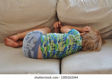 Cute 3 Year Old Boy Sleeping On The Couch, Taking His Midday Nap, In A Fetal Position