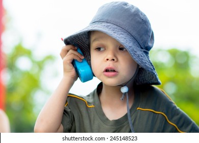 Cute 4 Year Old Mixed Race Asian Caucasian Boy Plays Outside In A Playground With A Toy Walkie Talkie Radio