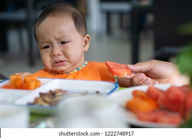 Cute 5-6 month asian baby girl doesn't want to eat watermelon.