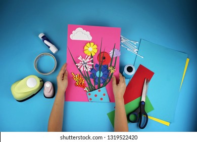 Cute 5  6 years old girl making spring DIY flowers and colored paper for her mom in Mothers Day  decorative punchers to create fun   easy and children  concept for kindergarten  top view