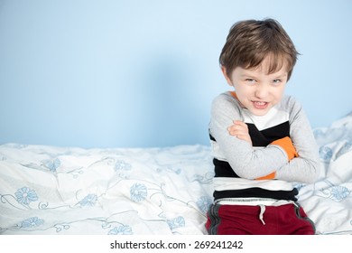 Cute 6 Year Old Boy Sitting On The Edge Of The Bed Happy With Crossed Arms