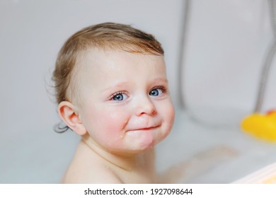 Cute adorable baby child taking bath in bathtub at home. Happy healthy boy or girl playing, splashing and having fun during bathtime. Hygiene and cleaning concept for babies.