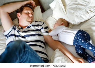 Cute Adorable Baby Girl Of 6 Months And Her Father Sleeping Peaceful In Bed At Home. Closeup Of Beautiful Child, Little Newborn Kid Sleeping. Tired Dad, Man In Bed With Daughter.