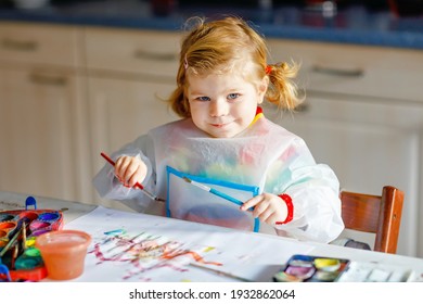 Cute adorable baby girl learning painting with water colors. Little toddler child drawing at home, using colorful brushes. Healthy happy daughter experimenting with colors, water at home or nursery - Powered by Shutterstock