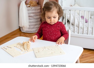 Cute adorable baby girl playing with puzzle in her room at home. Beautiful kid puzzling and making 3D crocodile model from wooden pieces. Child development and education concept. 