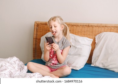 Cute Adorable Caucasian Girl Stay At Home And Call Her Friends On Smartphone. Child Kid Having Face Time Call Talk With People Relatives While On Self Isolation During Quarantine Of COVID-19.