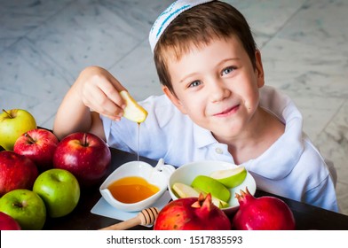 Cute adorable Caucasian Jewish child dipping an apple piece into honey on the Jewish New Year holiday of Rosh Hashanah concept image.