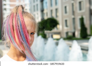 Cute adorable caucasian little kid girl and multicolored pastel chalk pained dyed blond hair city street and fountain background  Female child portrait pink colorful hairstyle smiling outdoors