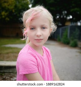 Cute adorable elementary school girl with bangs colored in pink. Adorable pretty Caucasian blonde girl kid with toned hair in bright color outdoor. Cool stylish fancy hipster kid. - Powered by Shutterstock