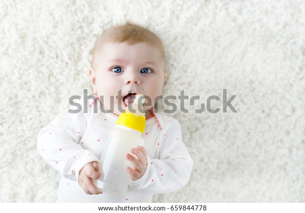 哺乳瓶とミルクを飲むかわいいかわいい赤ちゃん女の子 赤ん坊の第一食 白い背景に横たわる新生の少女 家族 哺乳瓶のコンセプト の写真素材 今すぐ編集