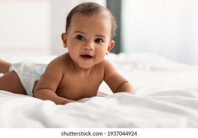 Cute adorable little African American kid lying on bed