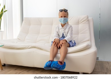 Cute Adorable Little Caucasian Blond Smiling Girl Sitting On Whilte Leather Luxury Sofa Waiting For Interview Or Meeting. Positive Cheerful Child In Room Before Visiting Medic Doctor