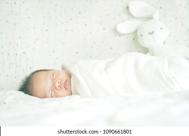 Cute Adorable Newborn Baby Boy Wrapped Or Swaddle In A Blanket, Sleeping  In Kids Bed