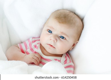 Cute adorable newborn baby in white bed on a blanket. New born child, little adorable girl looking surprised at the camera. Family, new life, childhood, beginning concept.
